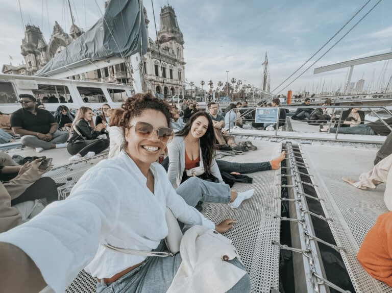 Ultimate Barcelona 5 Day Itinerary 10 This is an image of the author and her friend partaking in outdoor things to do in Barcelona. This shows the girls sitting on the catamaran, waiting for the boat to leave the dock to begin their Jazz Cruise.