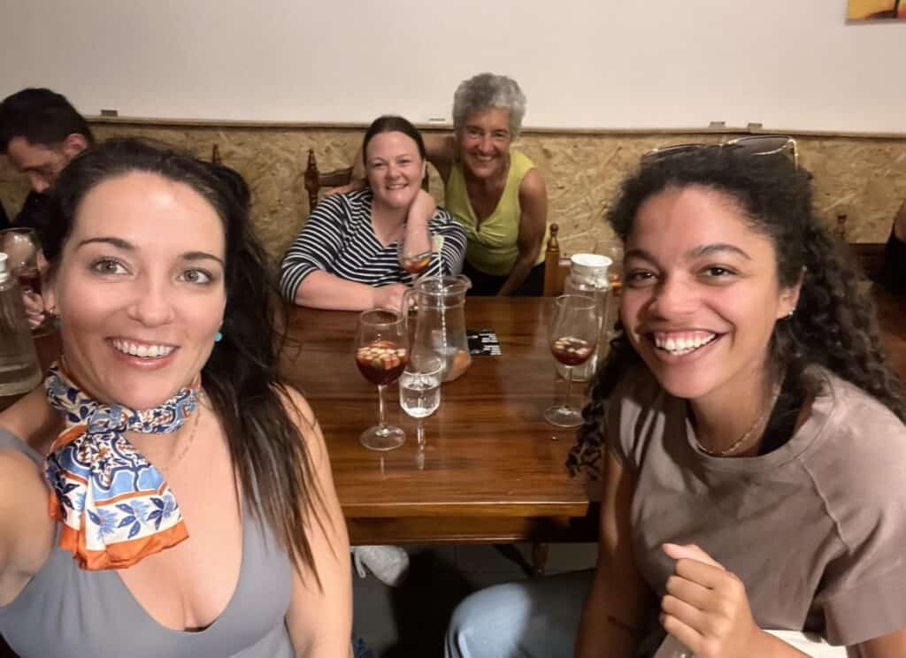 16 Ways to Deal With Loneliness as a Remote Worker 6 Person with a group of people she met while traveling. They are sitting around a table having a drink.