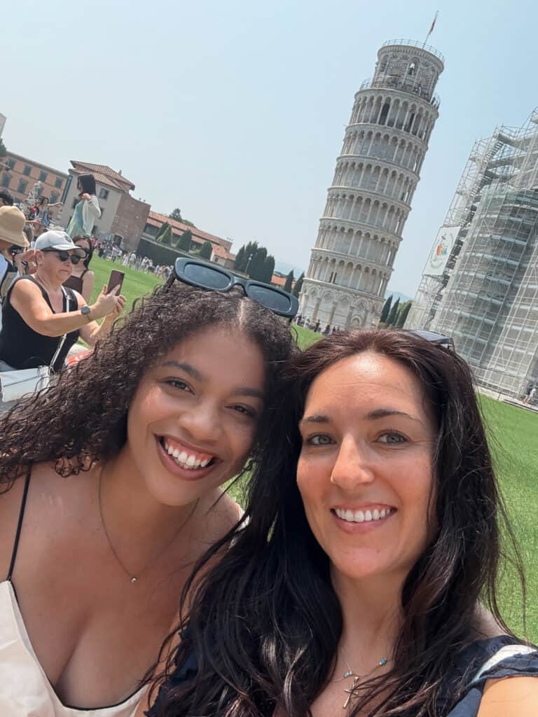 Home 14 Two girls smiling, standing in front of the Tower of Pisa.